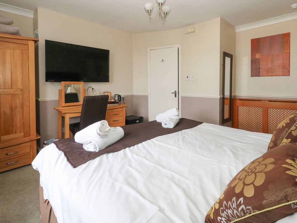 A bedroom with a bed, wardrobe, desk and television at 9 The Esplanade