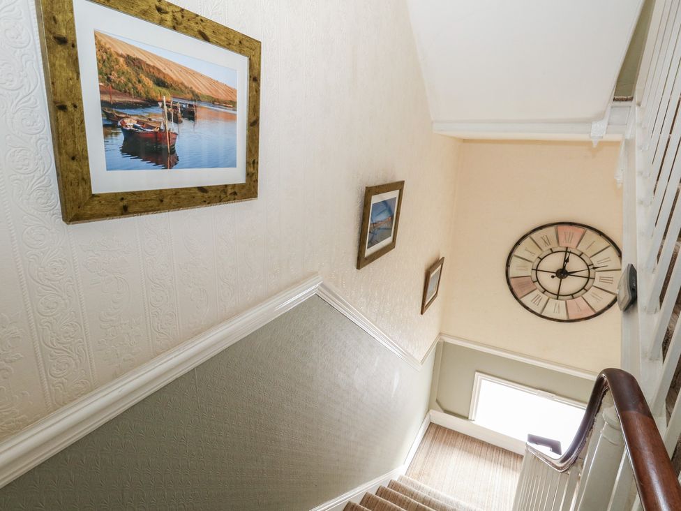 A staircase with pictures on the wall and a clock at 9 The Esplanade