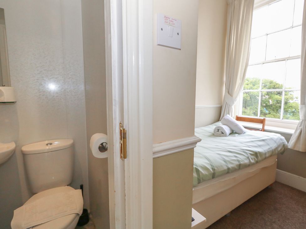 A bathroom with toilet and sink next to a bedroom with bed and window at 9 The Esplanade