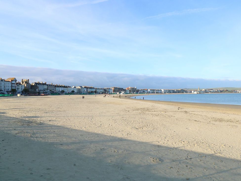 A beach with sand and buildings along the shore at 9 The Esplanade