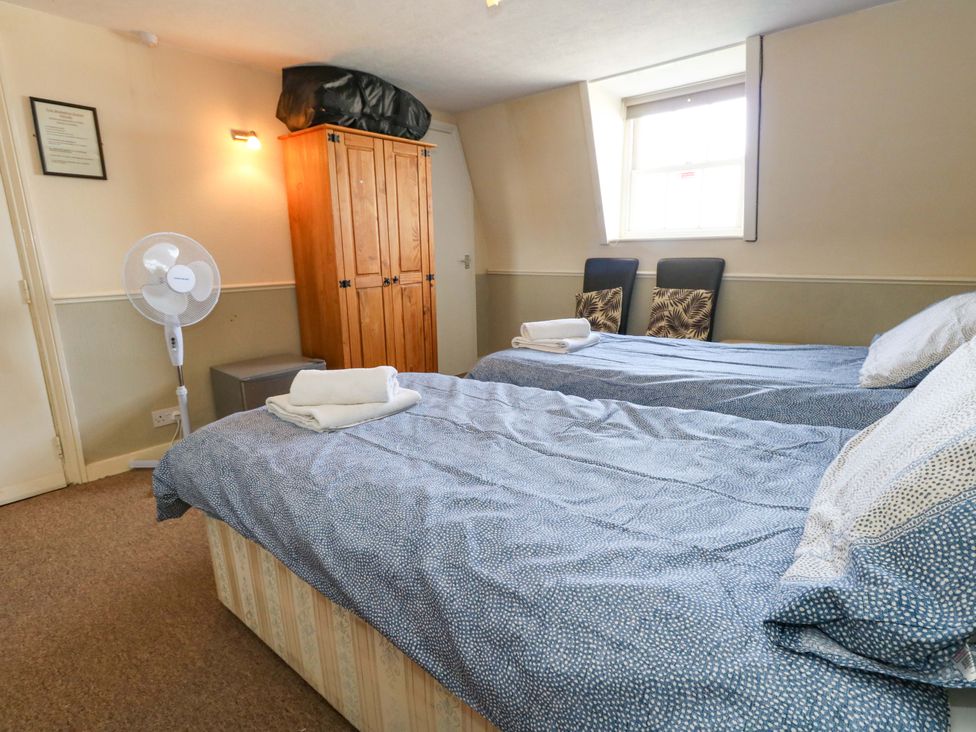 A bedroom with two beds and a wardrobe at 9 The Esplanade in Weymouth