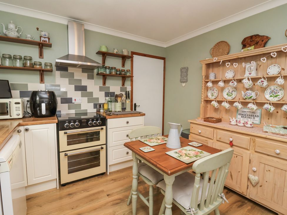 A kitchen with a stove and table at Ocean Cottage in Bude