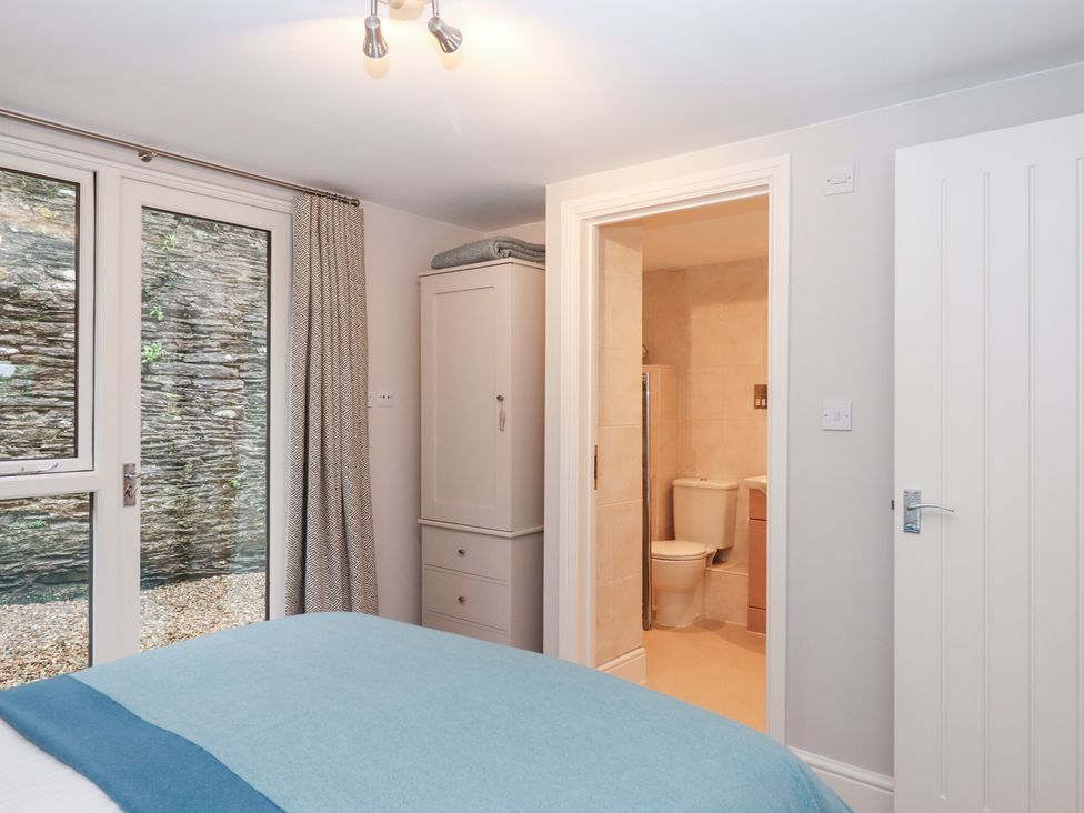 A bedroom with a wardrobe and a bathroom door at 3 Keepers Cottage