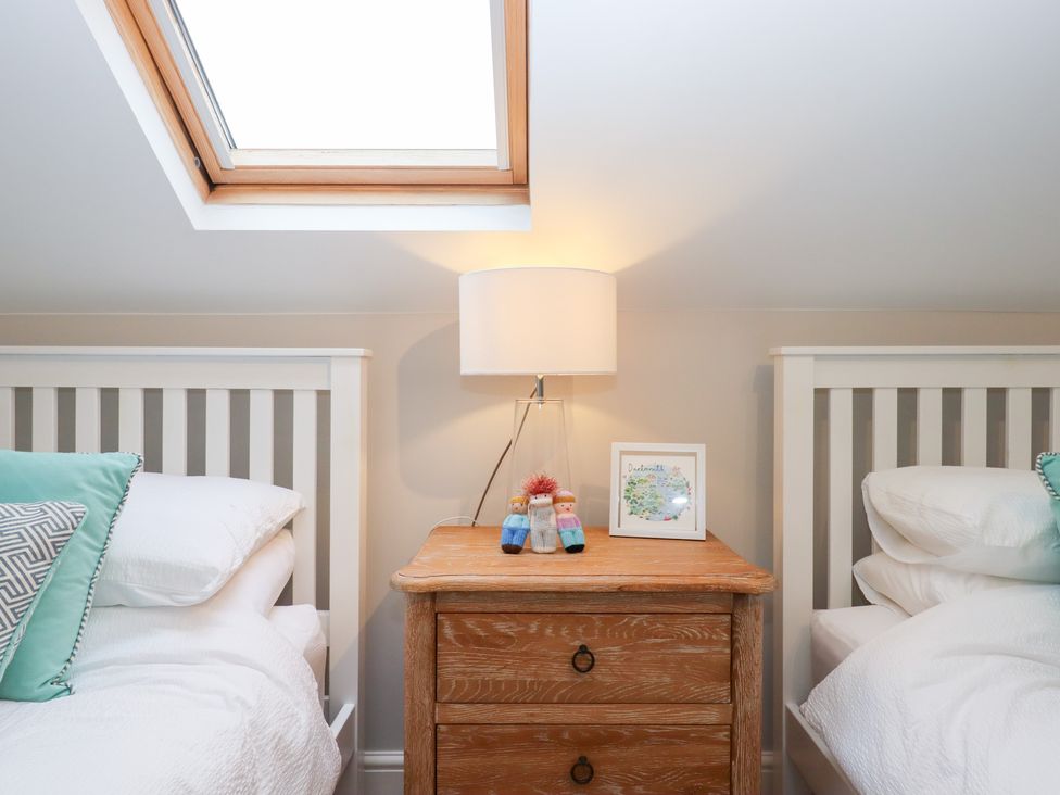 A bedroom with two beds and a bedside table at 3 Keepers Cottage