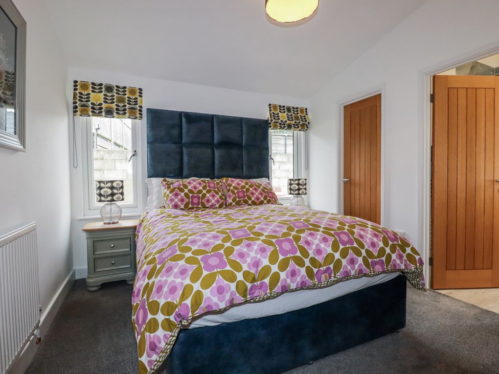 A bedroom with a bed and bedside table at Minack Lodge in Redruth