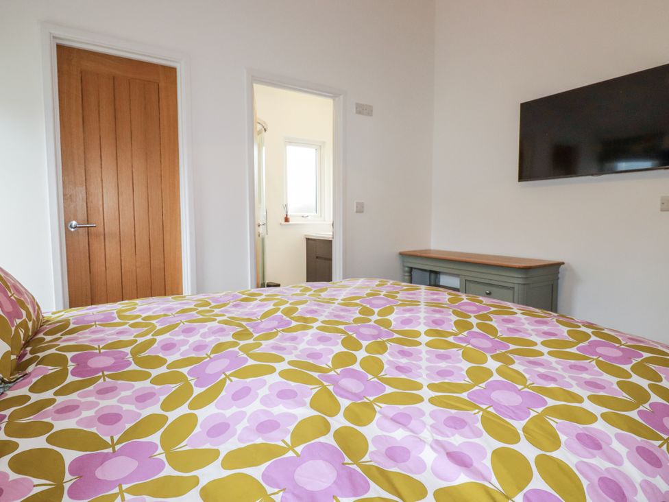 A bedroom with a bed and television at Minack Lodge in Redruth