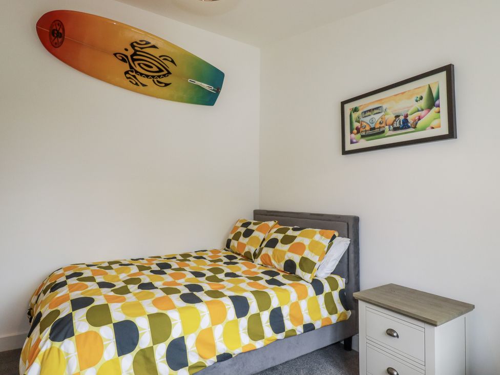A bedroom with a bed and surfboard on the wall at Minack Lodge in Redruth
