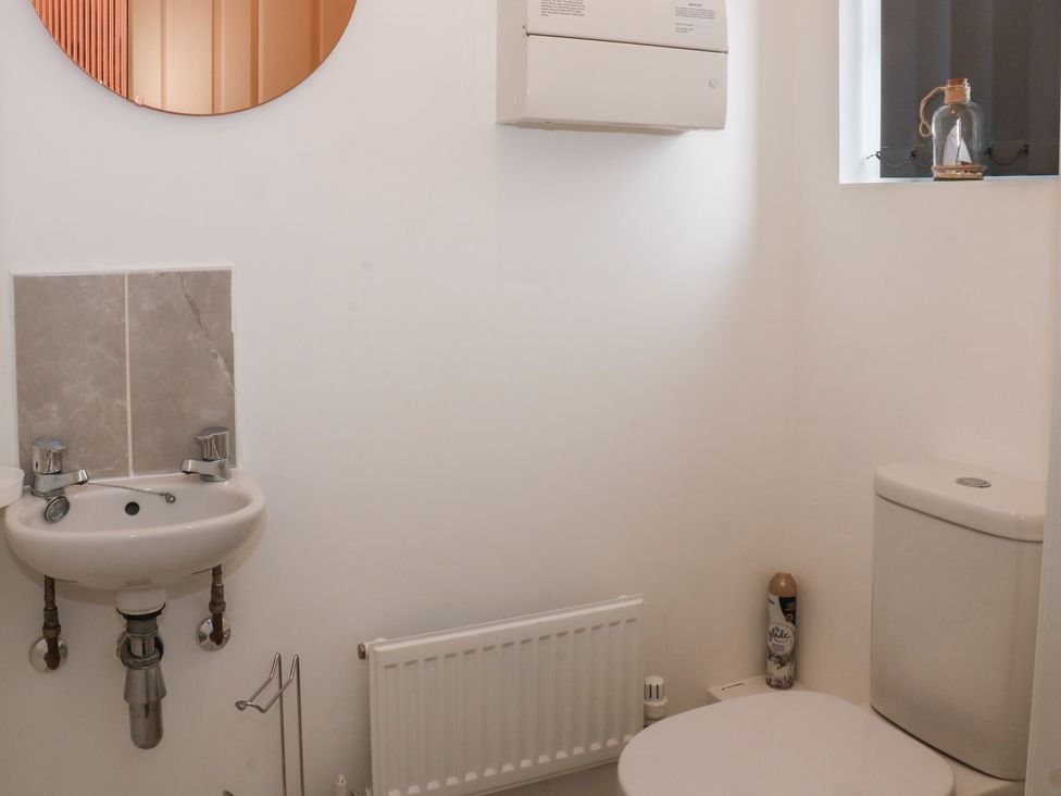 A bathroom with a sink, toilet, and mirror at Beach House Seaside Dunes, Lytham St. Annes