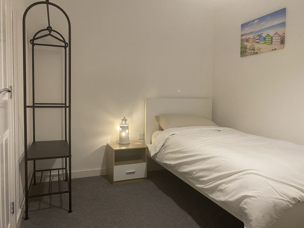 A bedroom with a bed and nightstand at Beach House Seaside Dunes in Lytham St. Annes