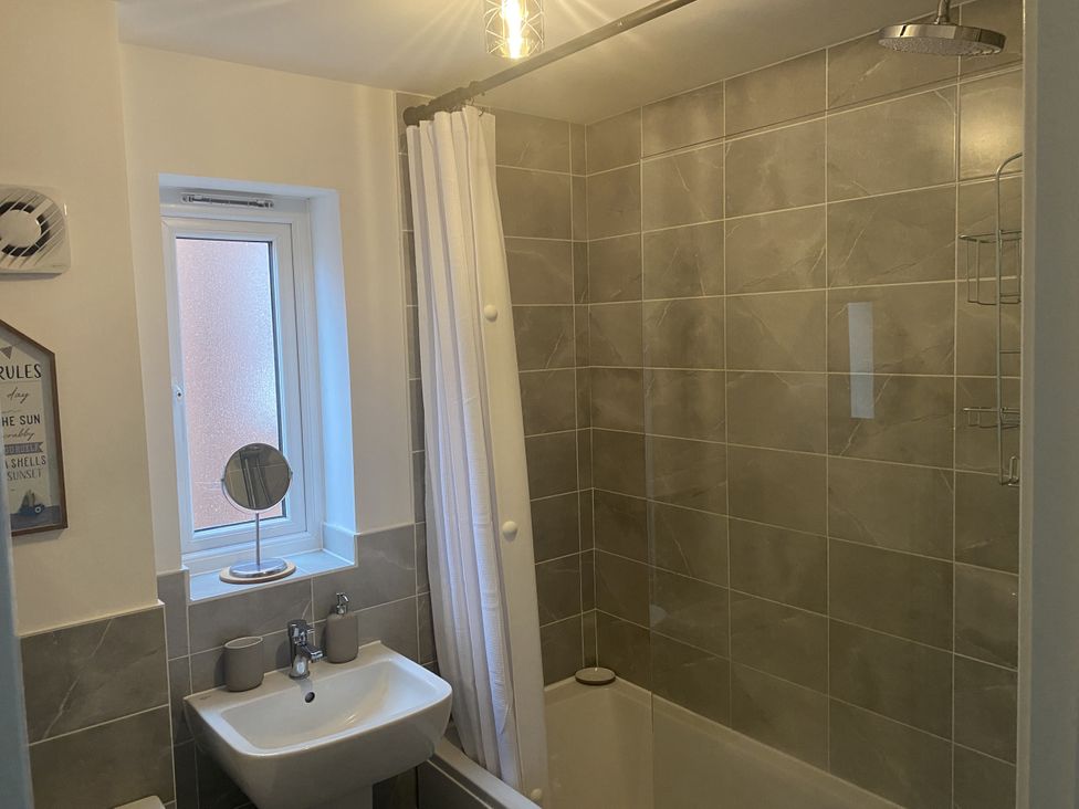 A bathroom with a shower, sink, and window at Beach House Seaside Dunes in Lytham St. Annes