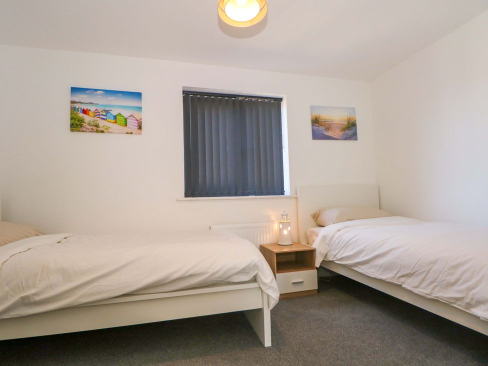 A bedroom with two beds and a nightstand at Beach House Seaside Dunes Lytham St. Annes