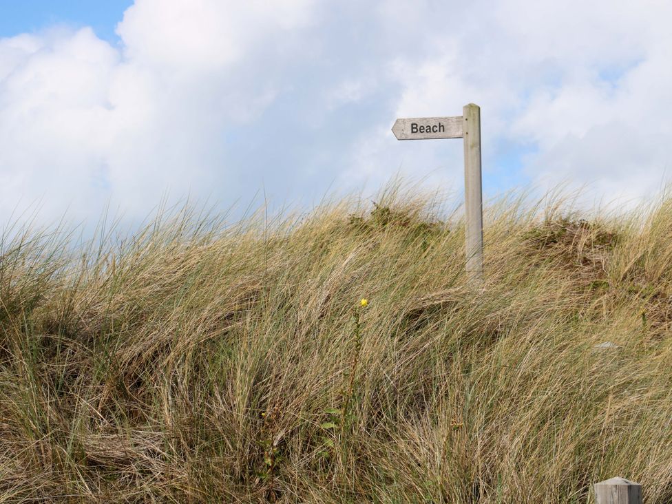 A signpost indicating the beach amidst grass at Beach House Seaside Dunes in Lytham St. Annes