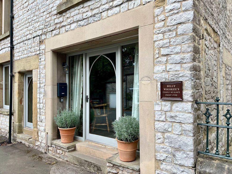 A stone entrance with a door and a sign at Billy Whiskey's in Tideswell