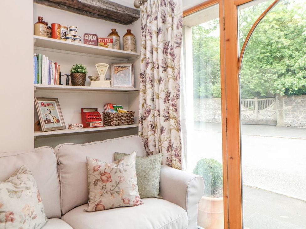 A living room with a shelf filled with books and decorative items at Billy Whiskey's in Tideswell