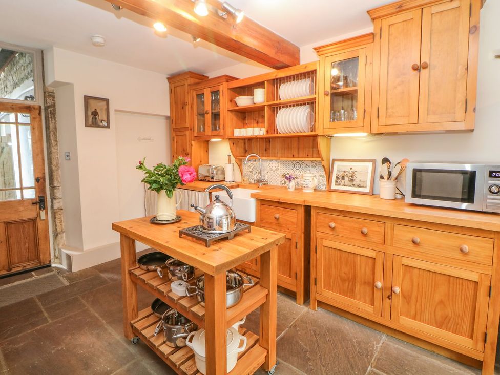 A kitchen with wooden cabinets and a sink at Billy Whiskey's Tideswell
