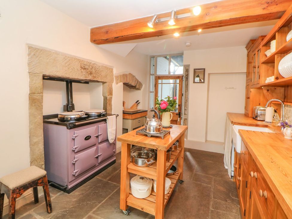 A kitchen with a stove and wooden furniture at Billy Whiskey's in Tideswell