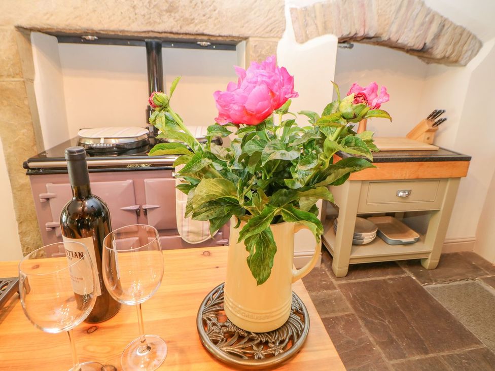 A kitchen with flowers, wine glasses, and a kitchen range at Billy Whiskey's in Tideswell