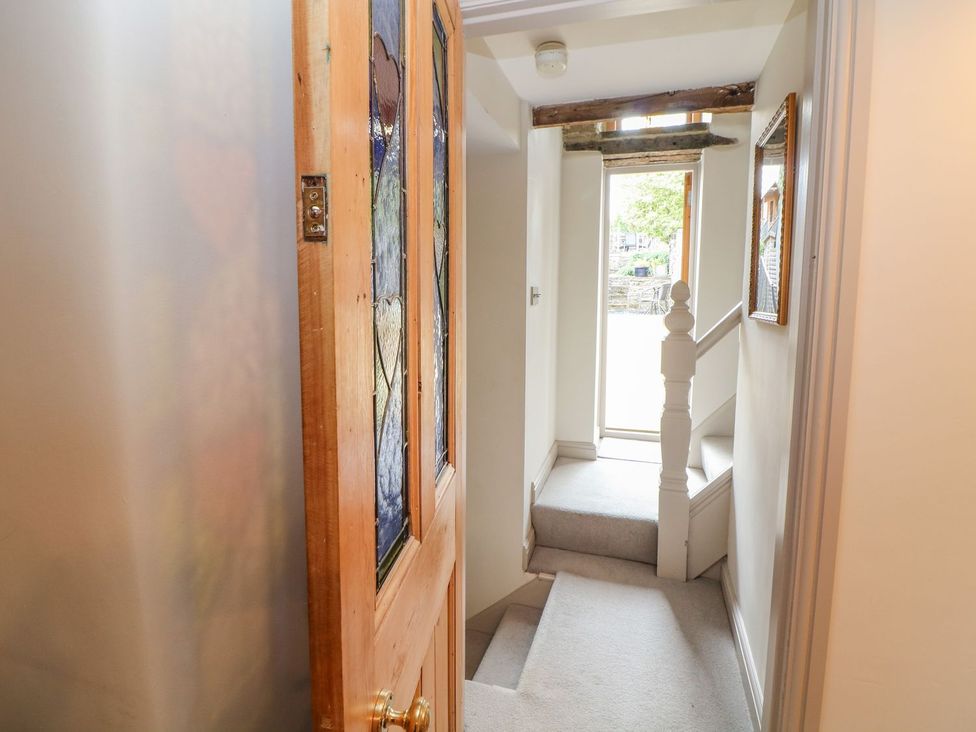 A hallway with a staircase and stained glass door at Billy Whiskey's in Tideswell