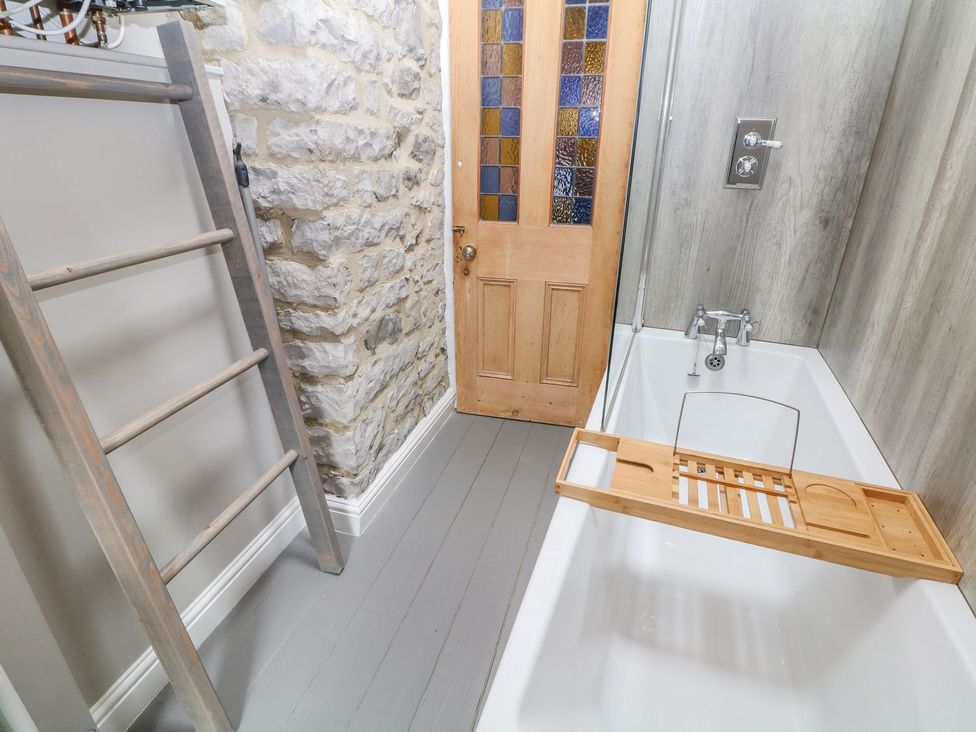 A bathroom with a bathtub and wooden bath tray at Billy Whiskey's in Tideswell