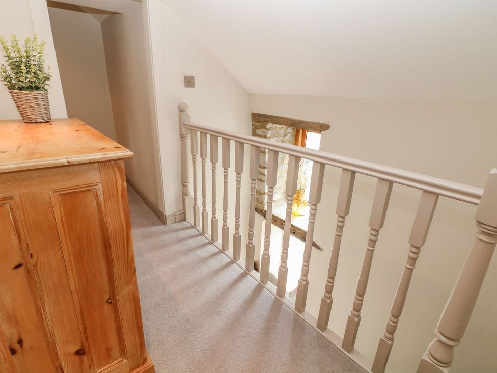 A hallway with a wooden cabinet and a railing at Billy Whiskey's Tideswell