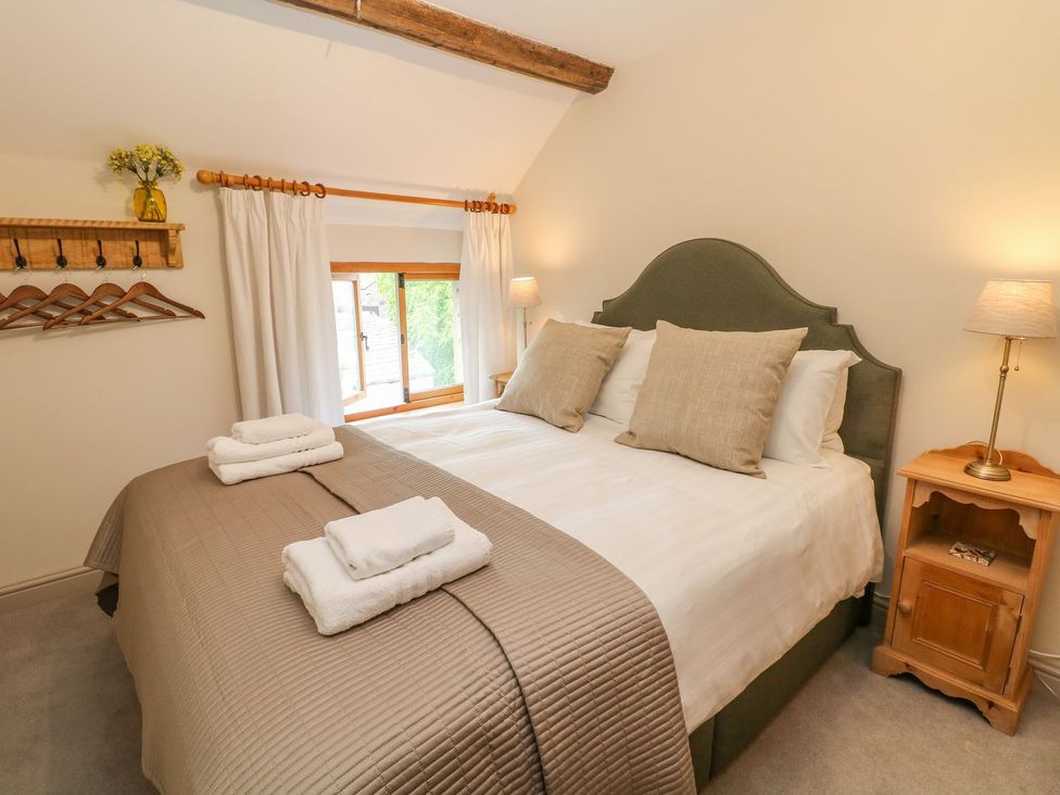 A bedroom with a bed, bedside lamp, and window at Billy Whiskey's in Tideswell
