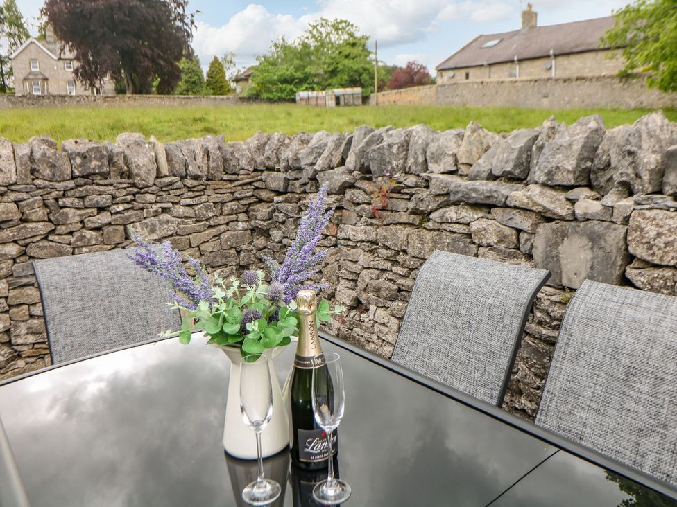 A table with a champagne bottle and glasses in an outdoor seating area at Billy Whiskey's in Tideswell
