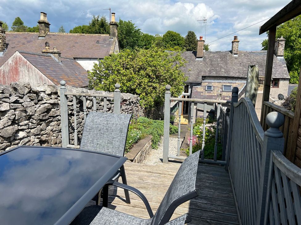 An outdoor area with a table and chairs overlooking gardens at Billy Whiskey's in Tideswell