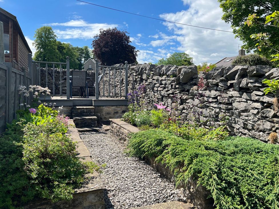 A garden with a stone pathway and furniture at Billy Whiskey's in Tideswell