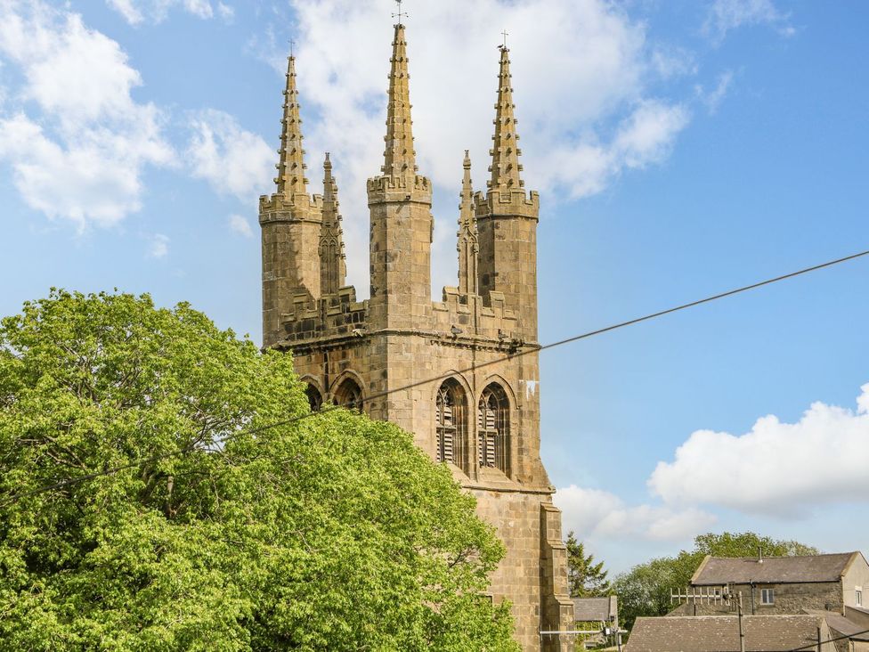 A church with spires and windows surrounded by trees at Billy Whiskey's in Tideswell