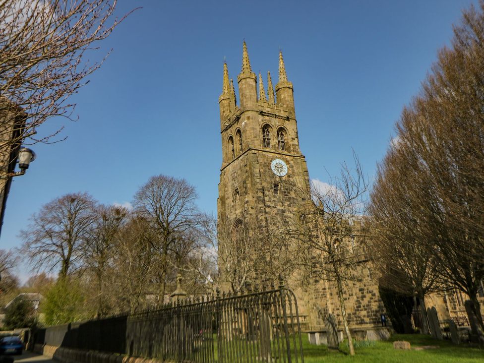 A church with a clock tower and trees at Billy Whiskey's in Tideswell