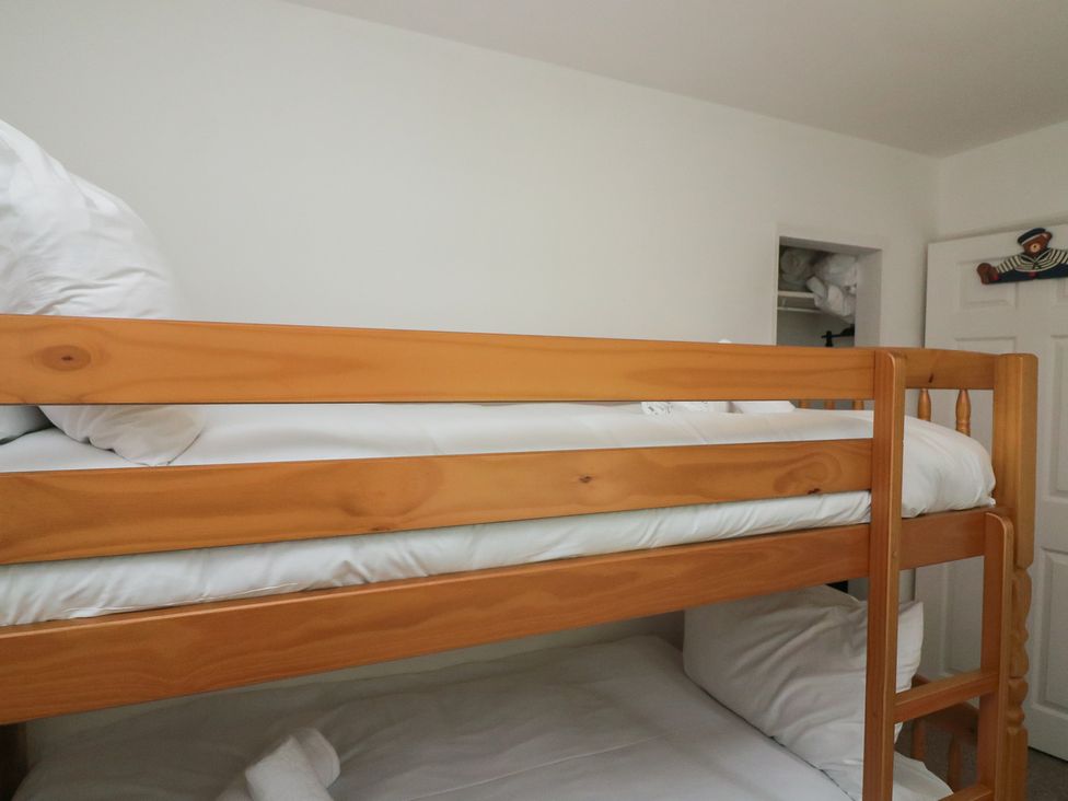 A bunk bed with white bedding and a closet in the background at Tapps Lodge in Plymouth