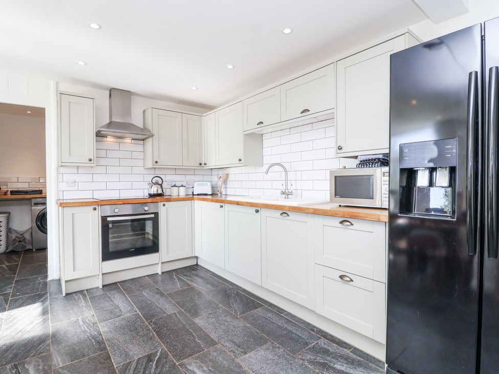 A kitchen with cabinets, refrigerator, oven, and sink at Tapps Lodge Brixton near Yealmpton, South Devon
