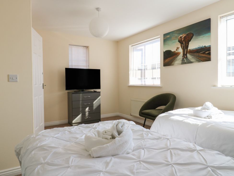 A bedroom with two beds, a television, and an armchair at Gem Relax