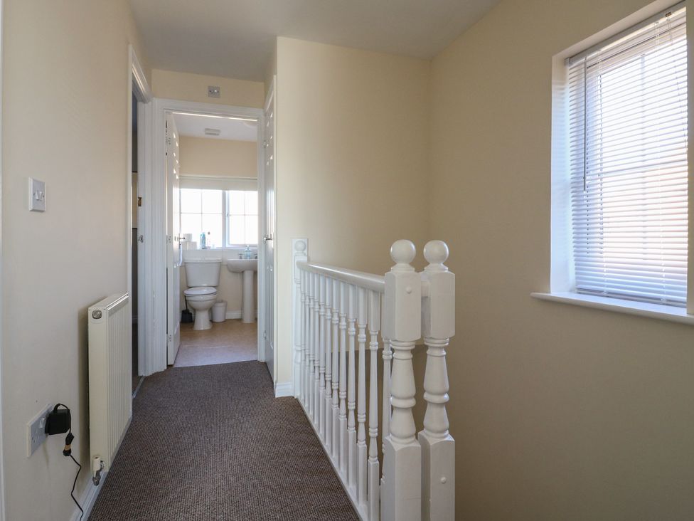 A hallway with a stair railing and a bathroom visible at Gem Relax 