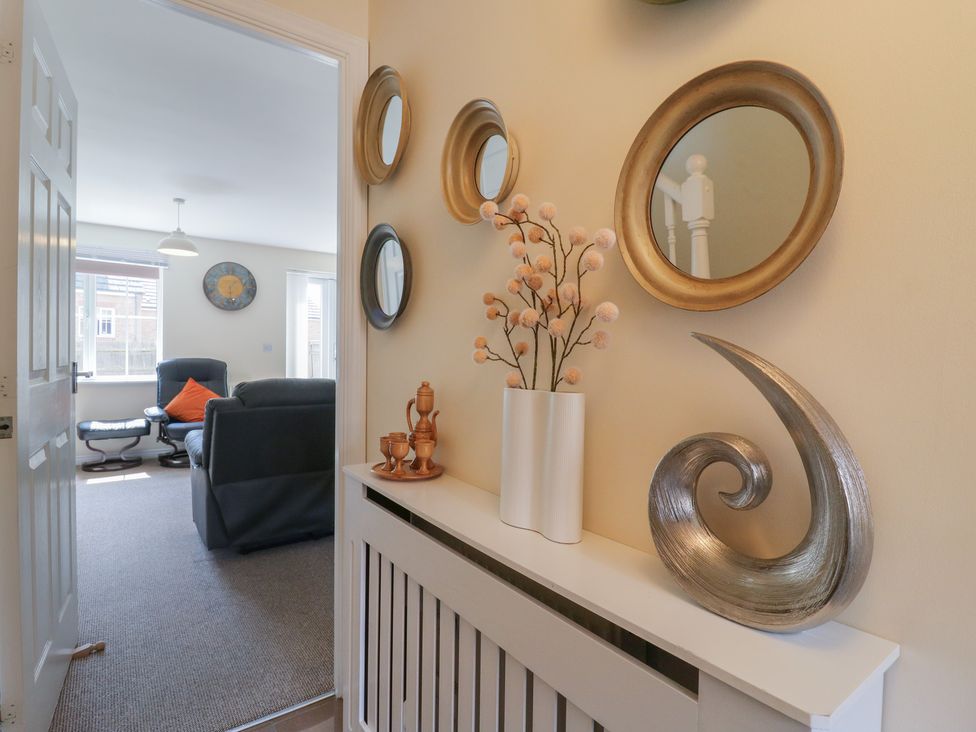 A hallway with mirrors and a flower vase at Gem Relax in Leighton Buzzard