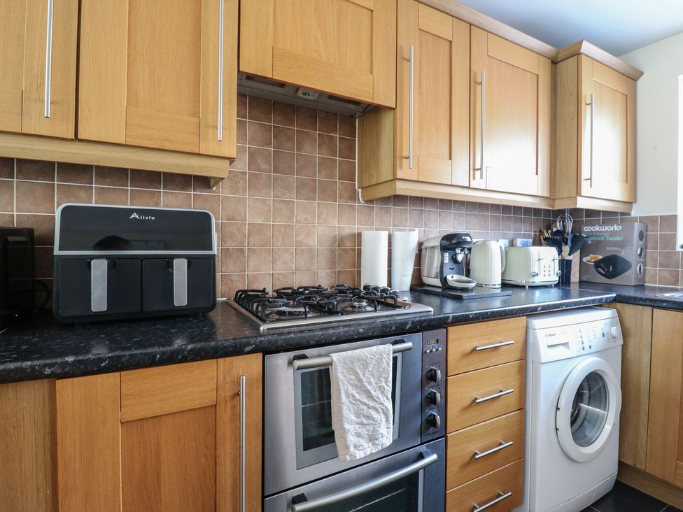 A kitchen with cabinets, oven, washing machine, and various appliances at Gem Relax in Leighton Buzzard