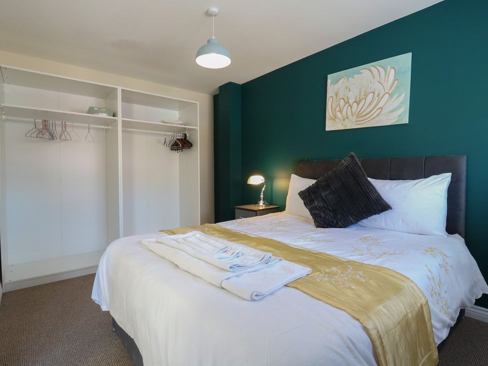 A bedroom with a bed, lamp, and wardrobe at Gem Relax in Leighton Buzzard