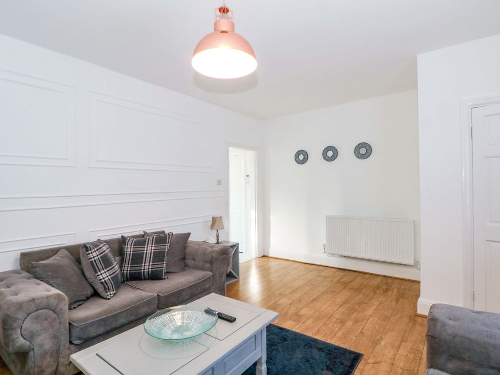 A living room with a sofa a coffee table and a light fixture at Ash House