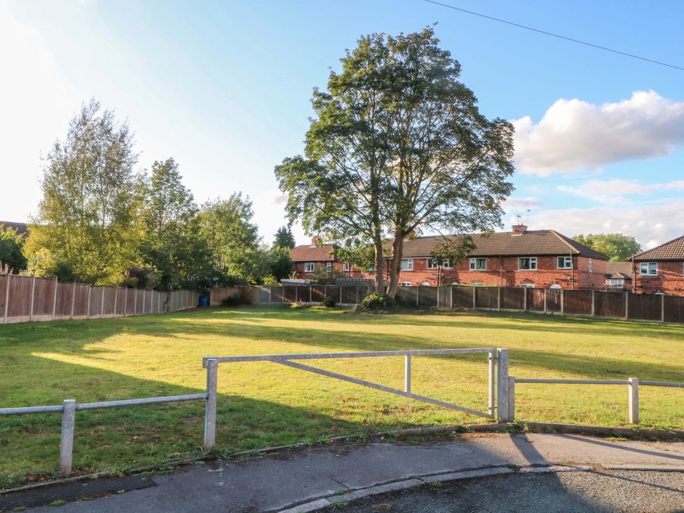 A grassy area with a tree and houses in the background at Ash House