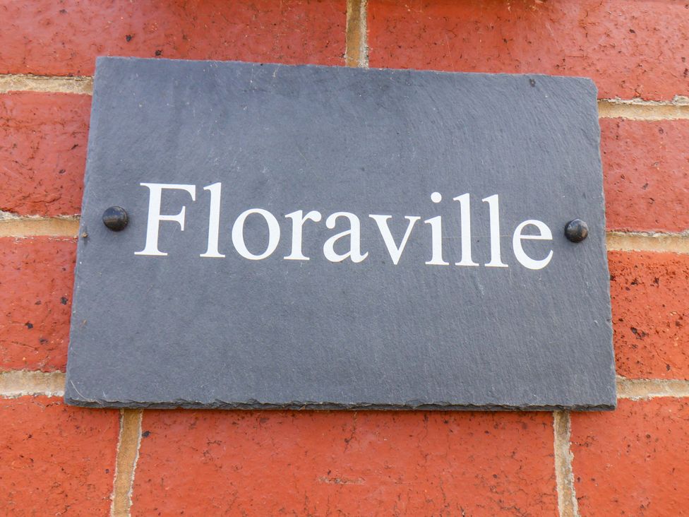 A slate sign with the name Floraville on a brick wall