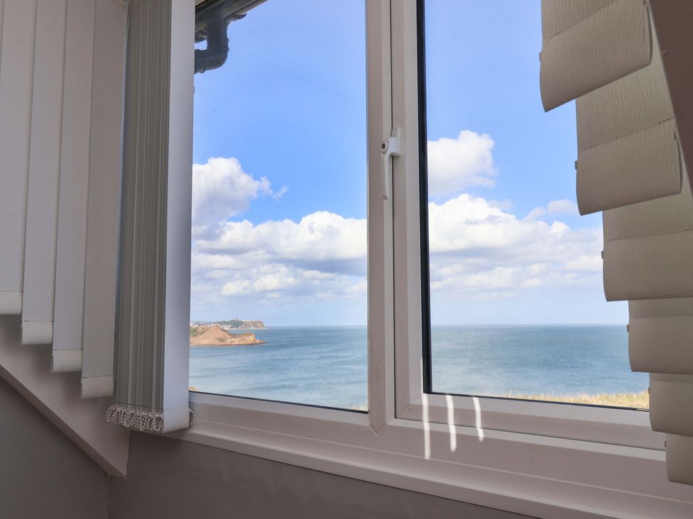A window with blinds overlooking the ocean at Floraville
