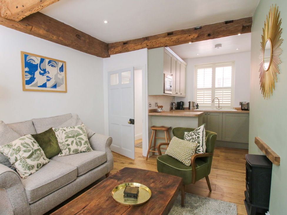 A living room with a sofa and kitchen area at Raven Lane Retreat in Ludlow
