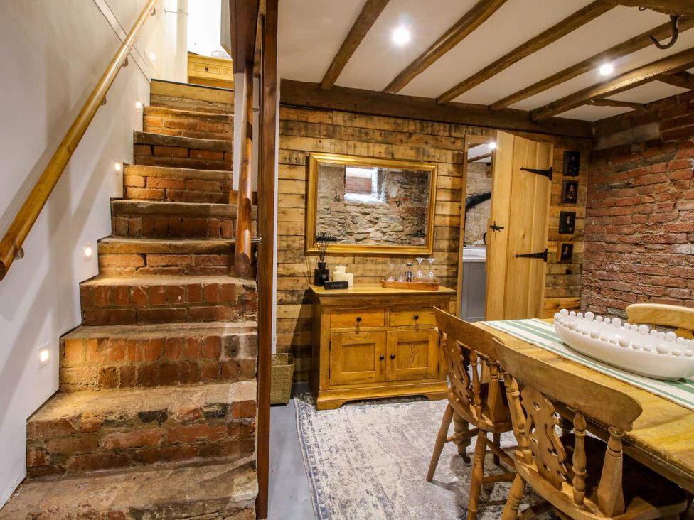 A dining room with wooden stairs, a table, and chairs at Raven Lane Retreat in Ludlow
