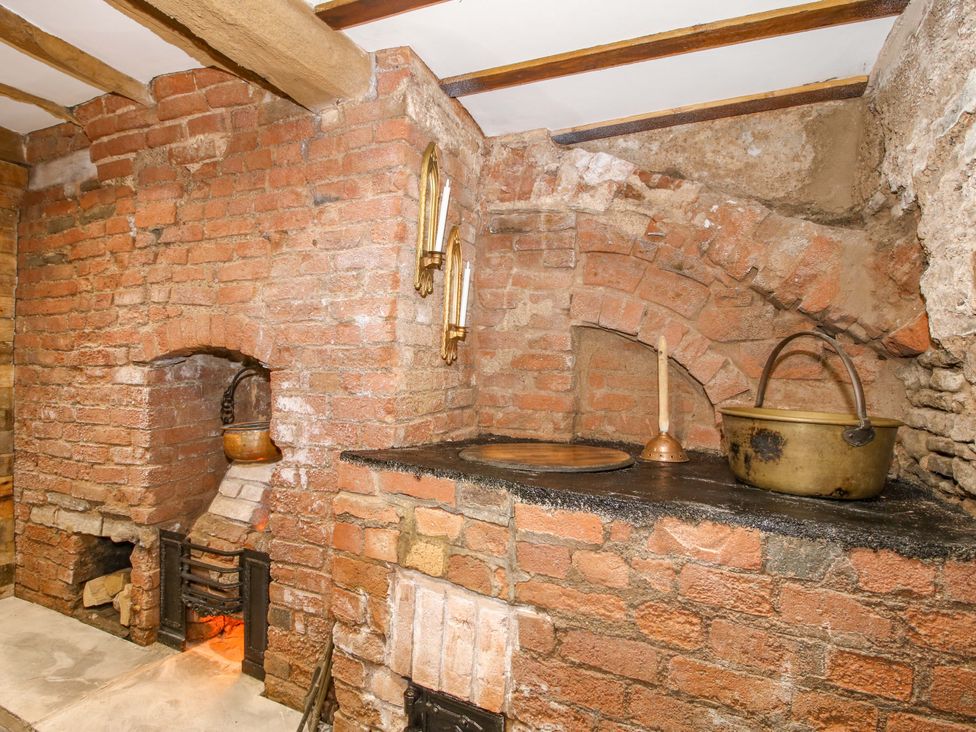 A kitchen with a brick wall and a fireplace at Raven Lane Retreat in Ludlow
