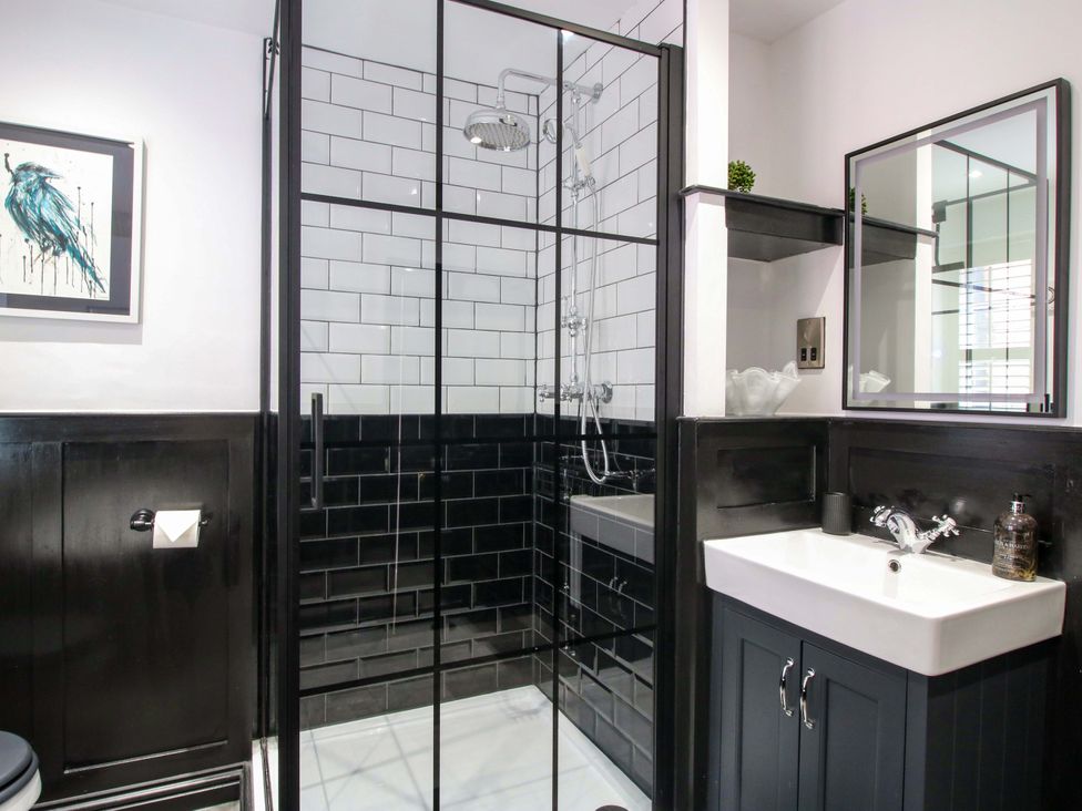 A bathroom featuring a shower, sink, toilet, and mirror at Raven Lane Retreat in Ludlow