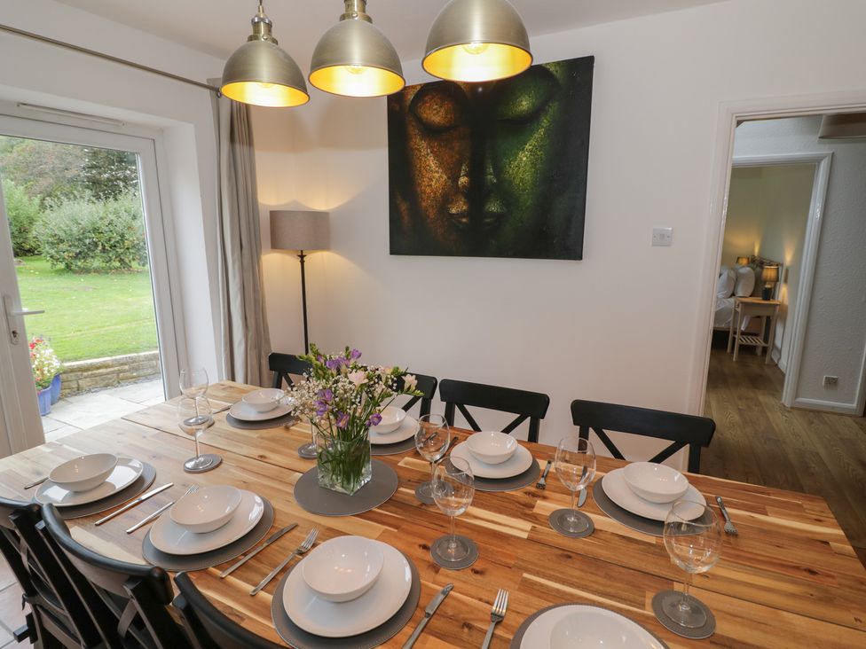 A dining room with a wooden table set for a meal at Harran in Pershore