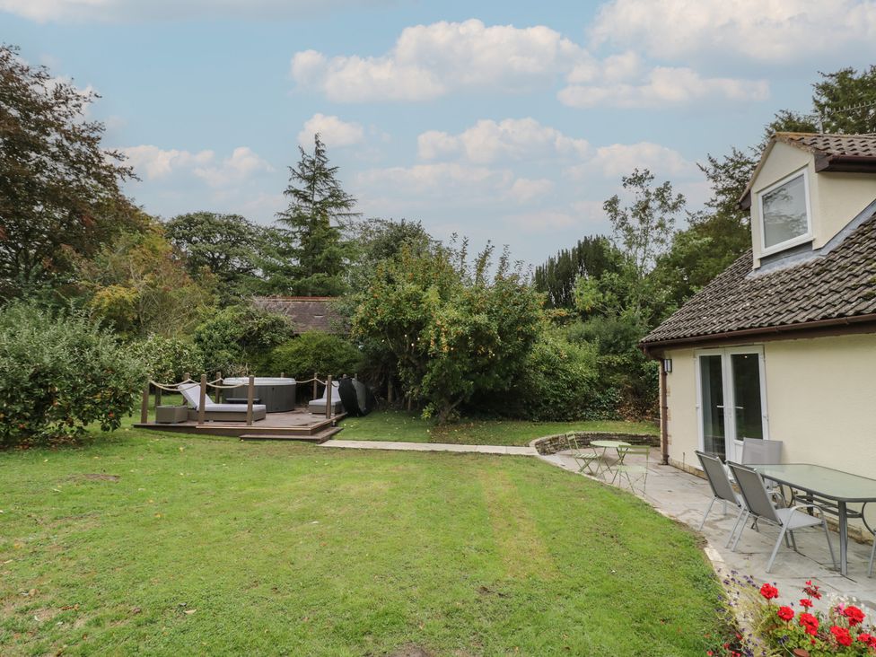 A garden with a house and deck area containing a hot tub at Harran in Pershore