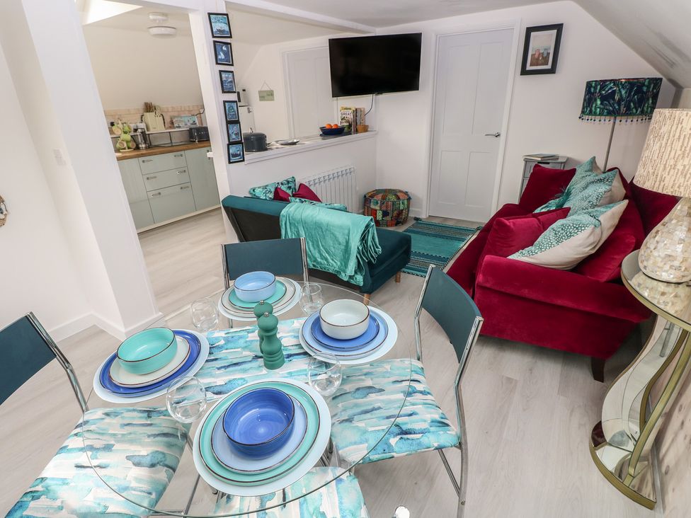 A living room with a sofa, dining table, and kitchen area at Over the way Cosheston near Pembroke