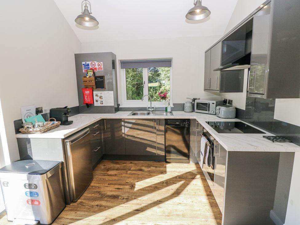 A kitchen with sink, fridge, and appliances at Dwrgi in Llanybydder