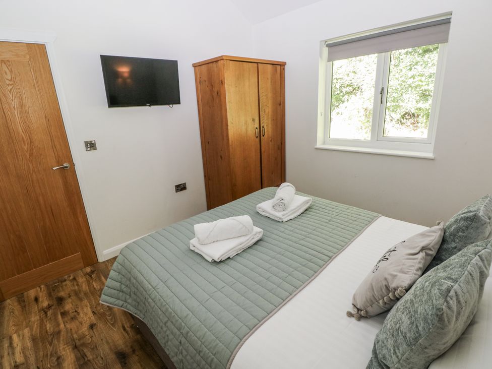 A bedroom with a bed, towels, wardrobe and a television at Dwrgi in Llanybydder